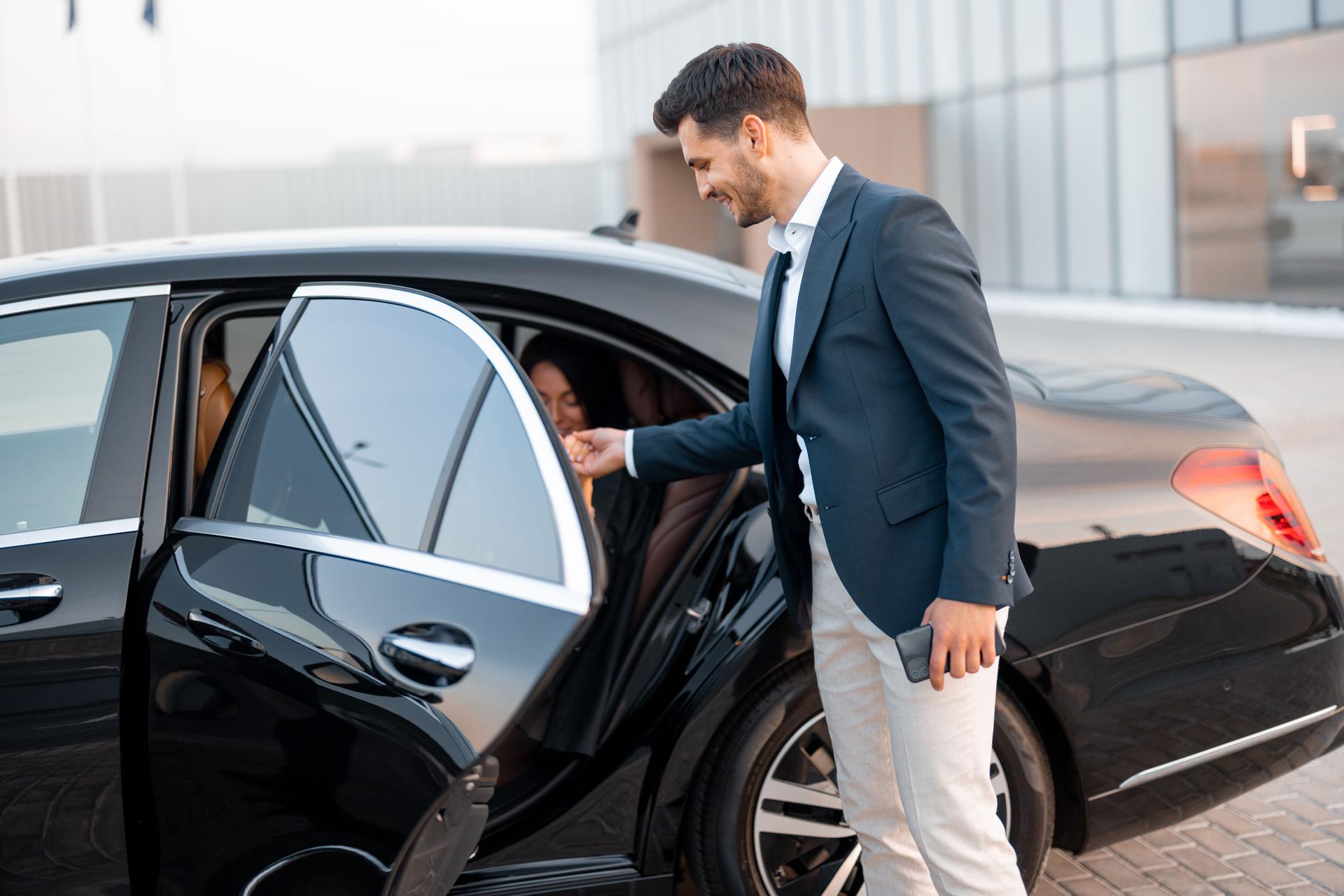 Businessman helps a woman to get out of a car