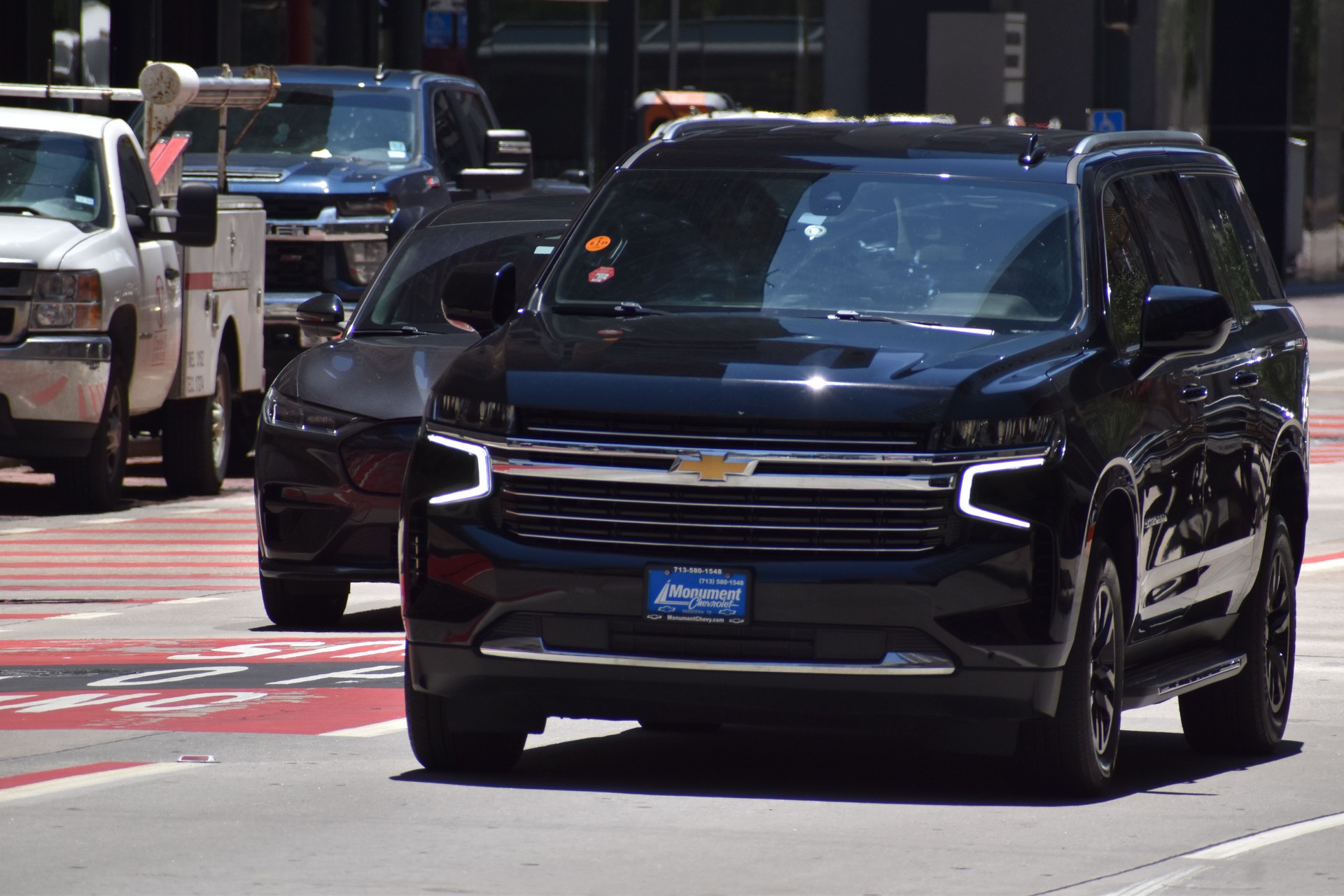 A portrait of a black Chevy Suburban SUV cruising in a financial district