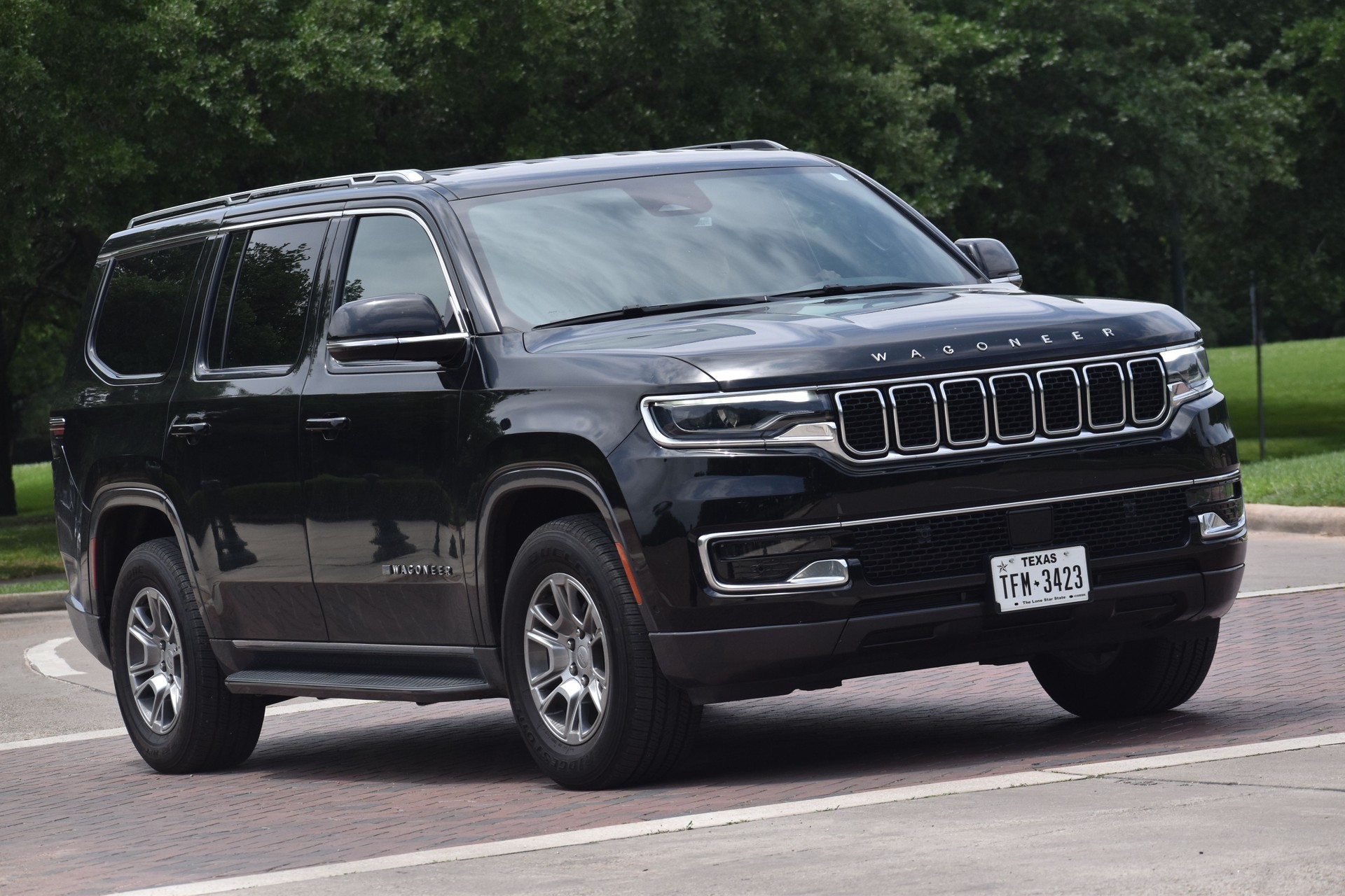 A black Jeep Wagoneer cruising near a nature reserve